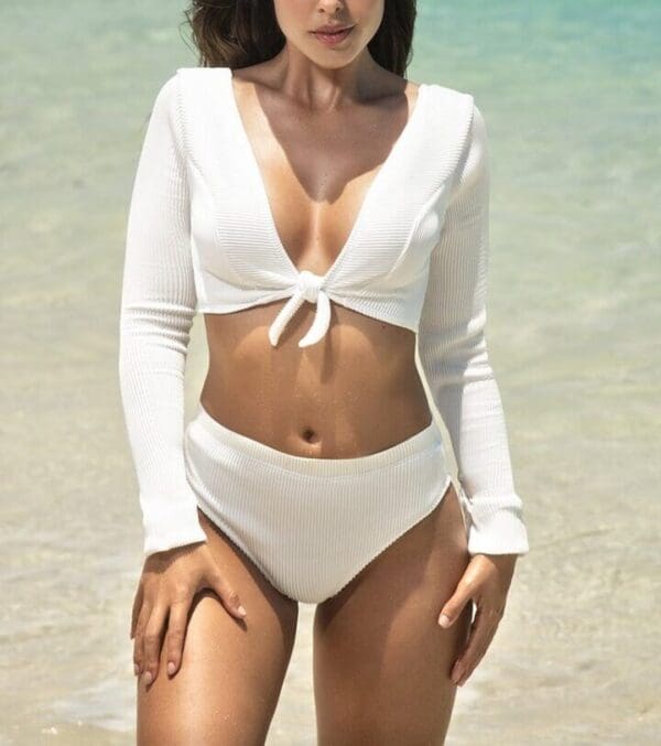 A woman in white bikini standing on the beach.