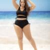 A woman in black swimsuit standing on the beach.