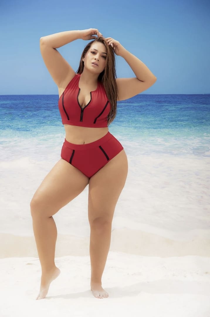 A woman in red bikini standing on the beach.