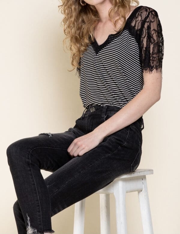 A woman sitting on top of a stool wearing black pants.