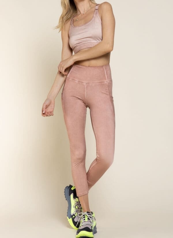 A woman in pink pants and top standing on one leg.