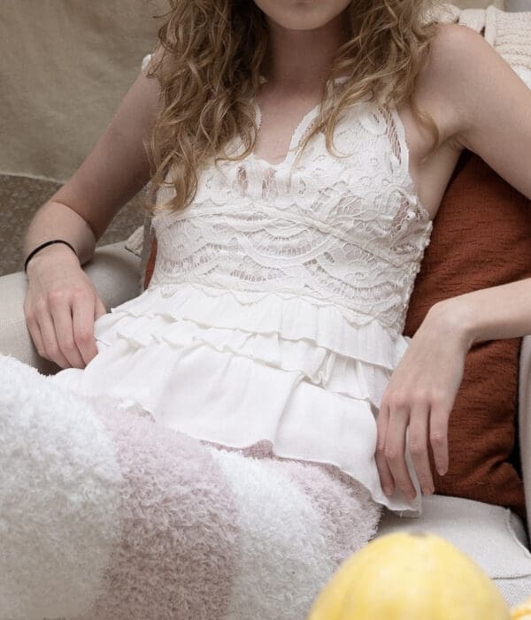 A woman sitting on top of a couch wearing white.