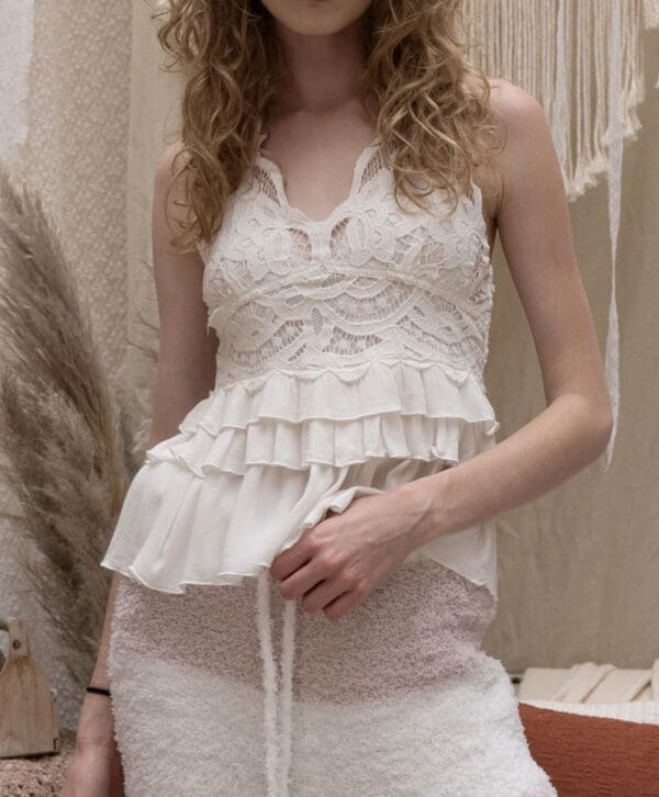 A woman in white dress standing next to a wall.