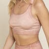 A woman wearing a pink sports bra and matching pants.