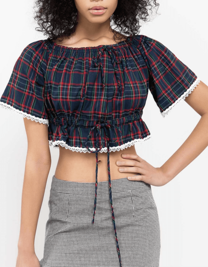 A woman wearing a plaid top and skirt.