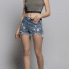 A woman wearing denim shorts and a crop top.