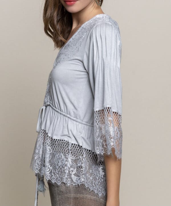 A woman wearing a gray top with lace sleeves.