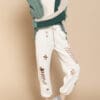 A person standing on the side of a wall wearing white pants.