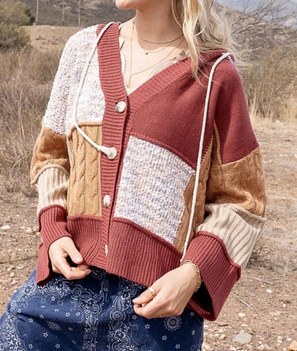 A woman sitting on the ground wearing a sweater.