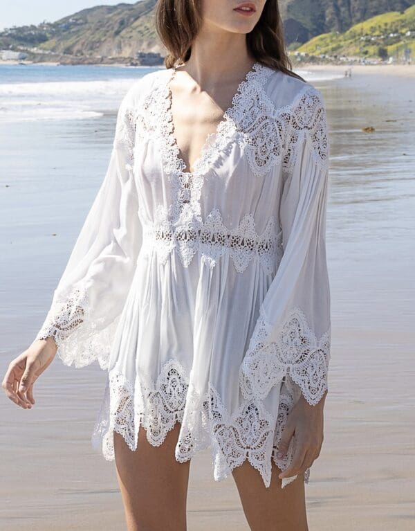 A woman in white dress standing on the beach.