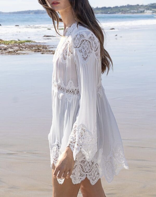 A woman in white dress standing on the beach.