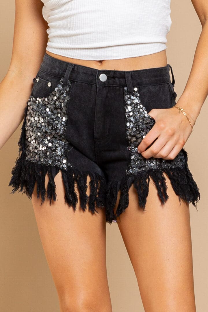 A woman wearing black shorts with sequins and fringes.