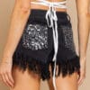 A woman wearing black shorts with white lace and sequins.