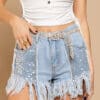 A woman wearing denim shorts with sequins and fringes.