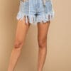 A woman wearing denim shorts with fringes and pearls.