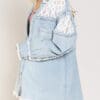 A woman wearing a denim jacket with lace sleeves.