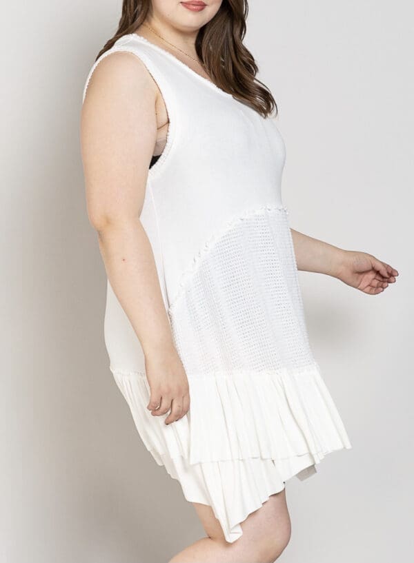 A woman in white dress standing next to wall.