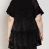 A woman wearing black is standing back to the camera.