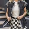 A woman in checkered shorts and denim vest.