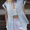 A woman wearing white shorts and a denim shirt.