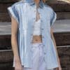 A woman wearing white shorts and a denim shirt.