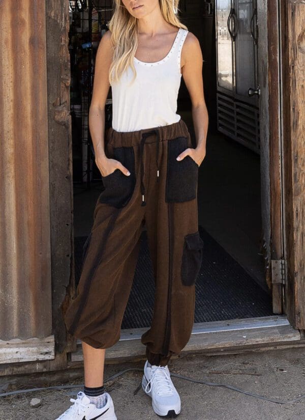 A woman wearing brown pants and white tank top.