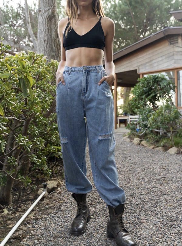 A woman standing on the ground wearing jeans.