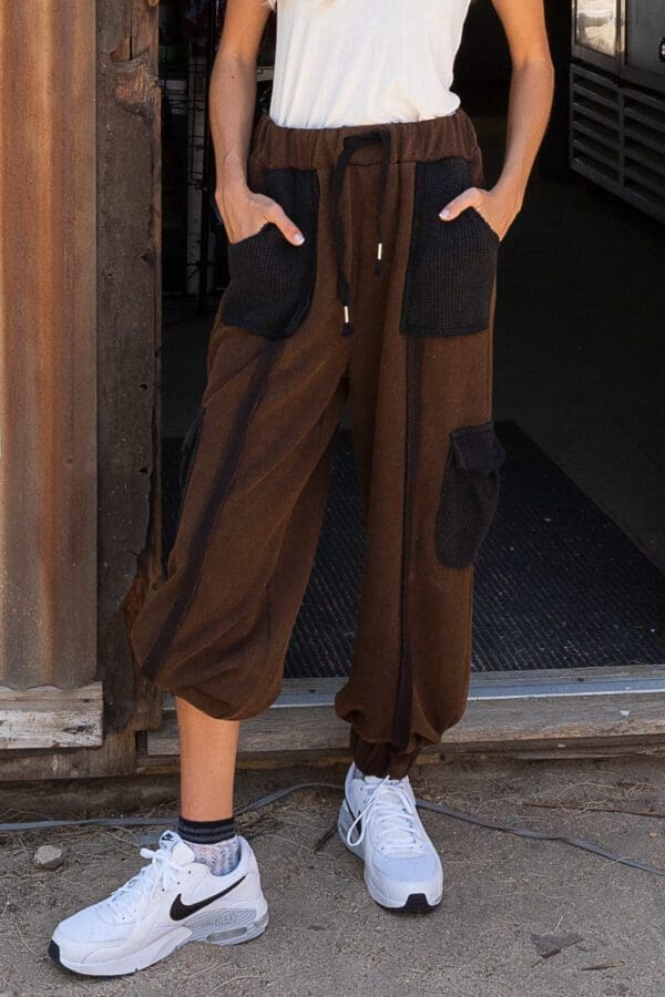 A person standing in front of a building wearing brown pants.