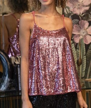 A woman in pink sequins is standing next to some flowers.