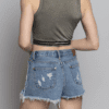 A woman wearing denim shorts and a crop top.