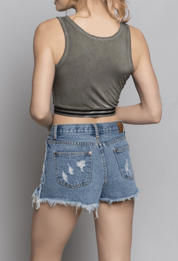 A woman wearing denim shorts and a crop top.