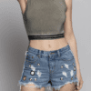 A woman wearing denim shorts and a crop top.