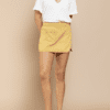 A woman wearing yellow shorts and white shirt.