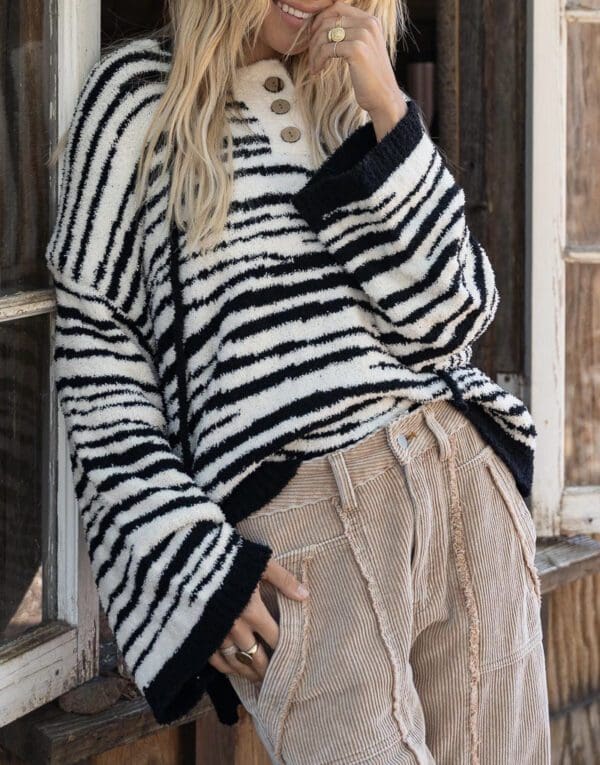 A woman standing in front of a window wearing a zebra print sweater.