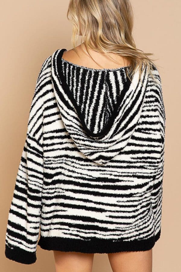 A woman wearing a zebra print sweater and jeans.