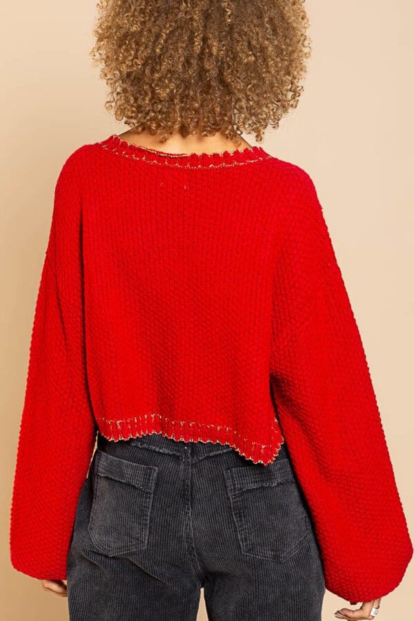 A woman wearing a red sweater and jeans.