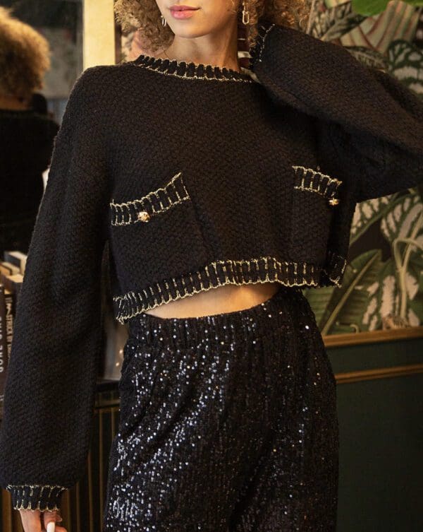 A woman in black sweater and sequins shorts.