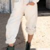 A person wearing white pants and green boots.