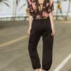 A woman in black pants and floral shirt.