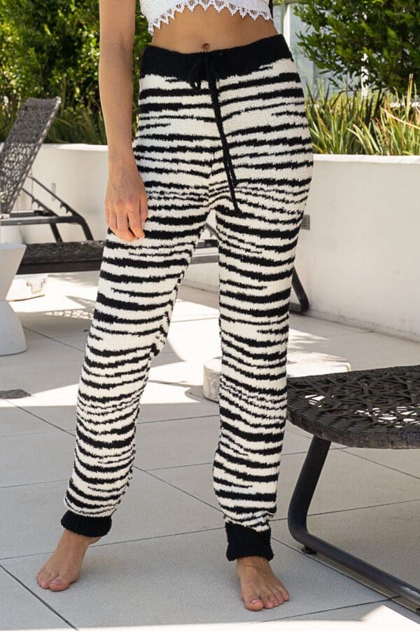 A woman standing on the ground wearing black and white pants.