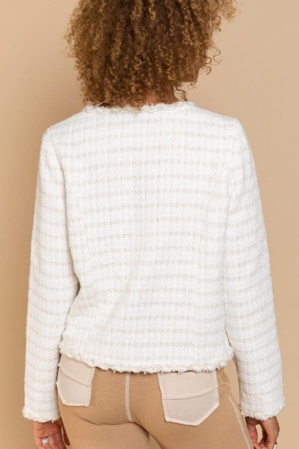 A woman wearing a white jacket with a fringed hem.