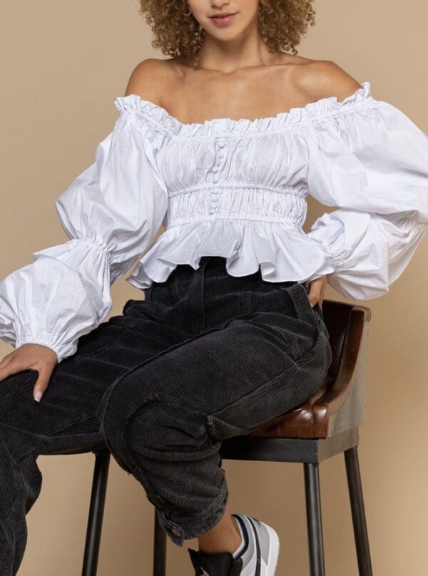 A woman sitting on top of a chair wearing black pants.