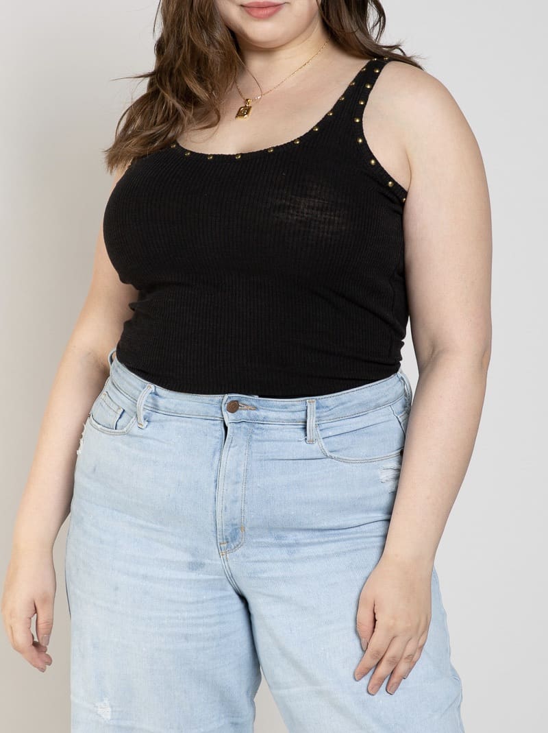 A woman wearing light blue jeans and black tank top.