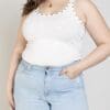 A woman wearing light blue jeans and white tank top.