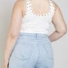 A woman wearing light blue jeans and white tank top.