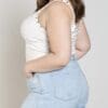 A woman in white tank top and blue shorts.