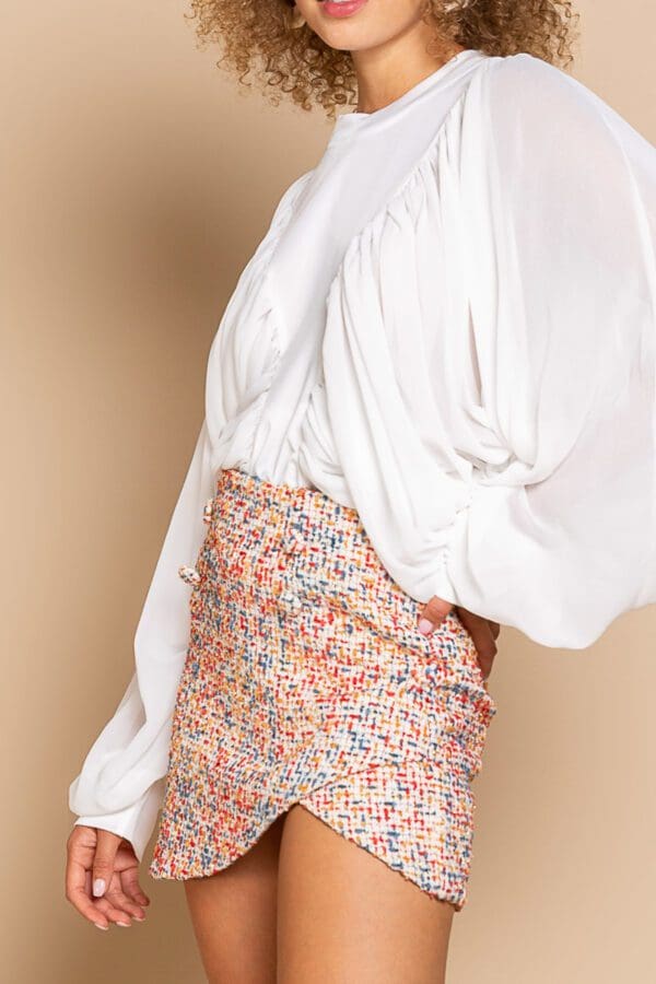 A woman wearing a white shirt and floral skirt.