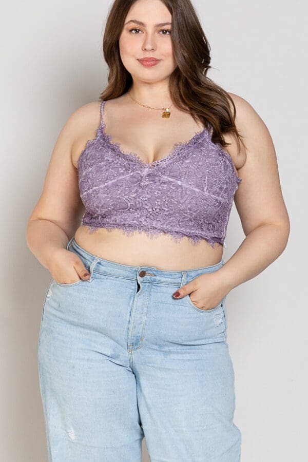 A woman wearing high waisted jeans and purple lace bra.