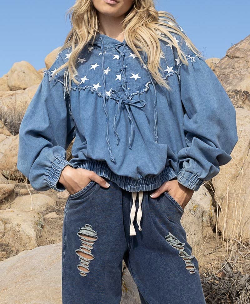 A woman standing in front of some rocks wearing blue jeans.