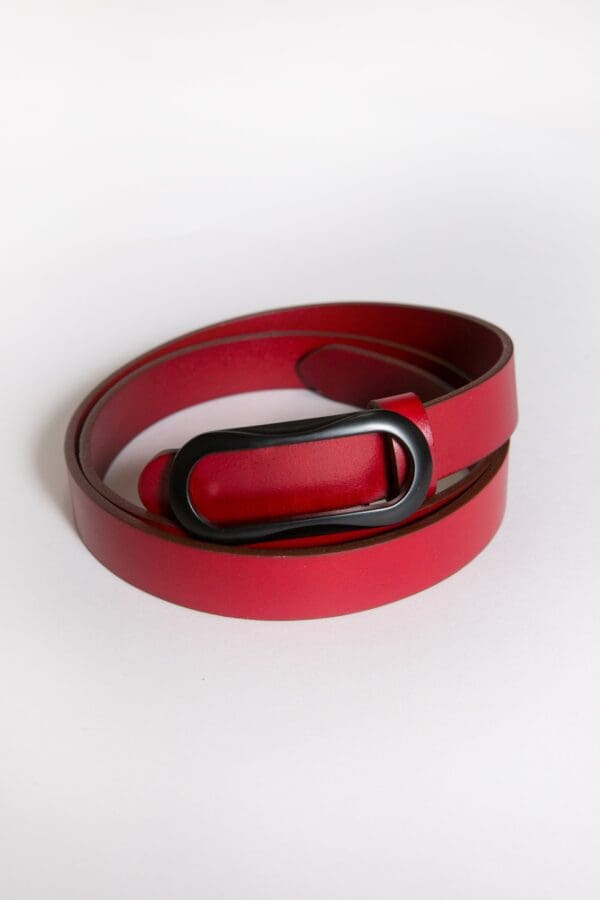 A red belt with black buckle on top of white surface.